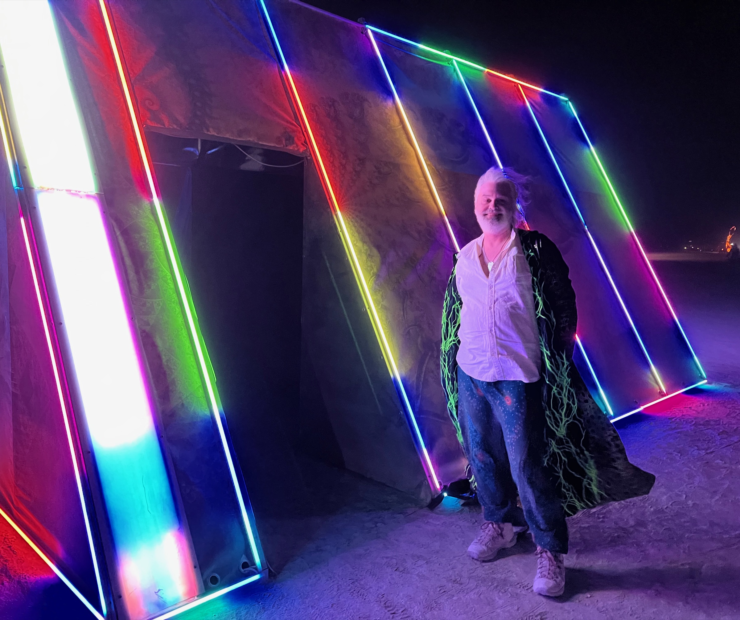 VIXT in front of VIXToscope II at Burning Man, rainbow LED edges glowing against the night playa